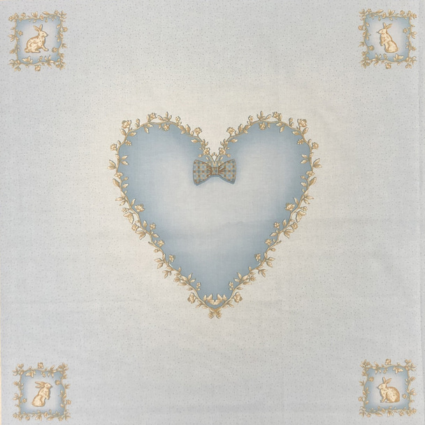 A blue square of fabric with bunnies and a heart centerpiece