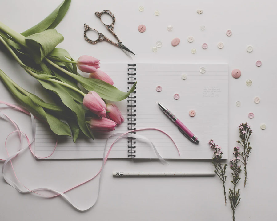 spread of pink flowers, buttons, scissors, and stationery
