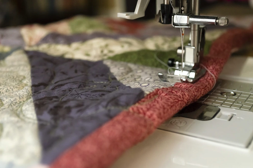 multi-colored quilt being fed through a sewing machine